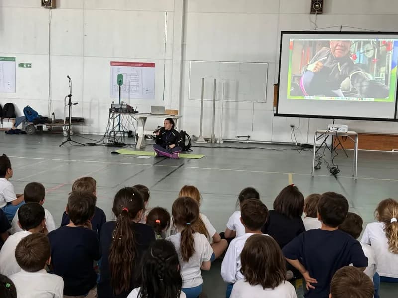 El gimnasio del colegio con el lienzo del Lycée Antoine de Saint-Exupéry: los estudiantes escuchan sentados en el suelo mientras se proyecta el documental.