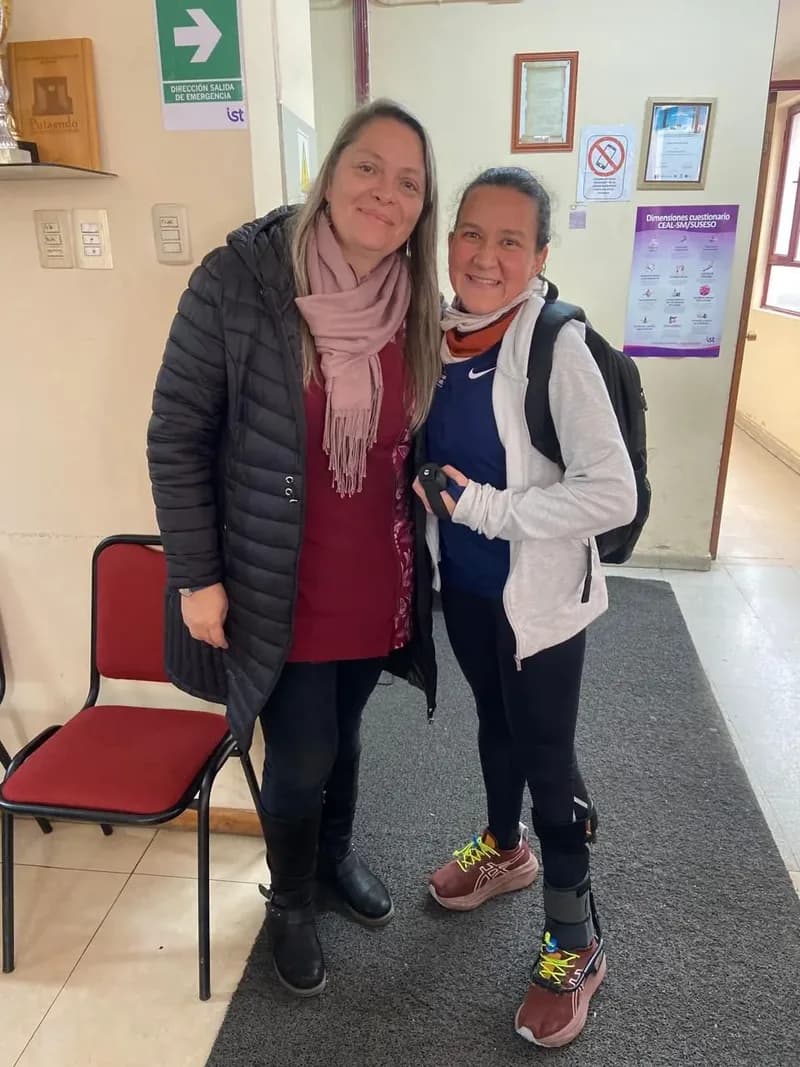 Macarena Larraín, con su mochila puesta, posa en un pasillo del colegio junto a una profesora.