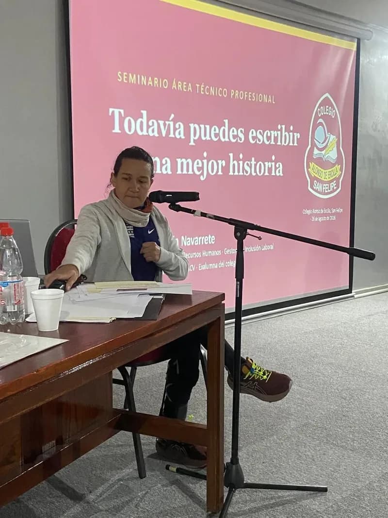 Macarena Larraín habla al micrófono desde la mesa del auditorio, frente a la pantalla que proyecta el título del seminario, «Todavía puedes escribir una mejor historia».