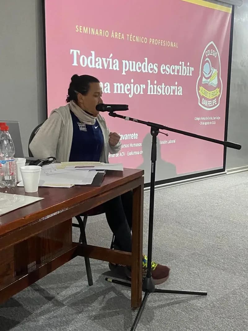 Macarena Larraín repasa sus apuntes sobre la mesa durante el seminario, con la presentación proyectada detrás.