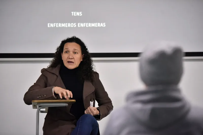 Macarena Larraín hablando, vista desde el público; detrás se proyectan los agradecimientos del documental.