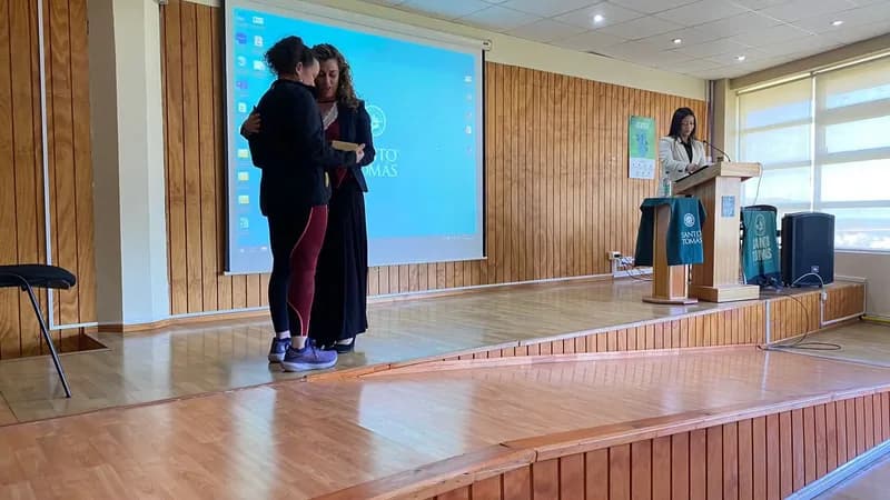 Macarena Larraín recibe un abrazo y un reconocimiento en el escenario al terminar su exposición.